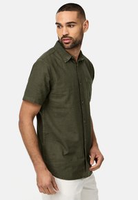 Kurzärmliges, olivgrünes Hemd mit Knöpfen aus einem weichen Stoff, mit einer Brusttasche, spitzem Kragen und geradem Saum.