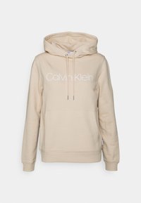 Béžová mikina s kapucí a přední kapsou, bílý logo "Calvin Klein", žebrované manžety a lem, vyrobená z měkké bavlněné směsi.