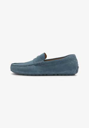 Blauwe suede instapper met mocassin-stiksel, rubberen zool, slip-on ontwerp en subtiele merknaam op de wreef. Gladde textuur en een lage profiel.
