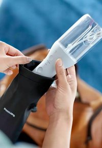 Draagbare blender in zwarte draagtas; witte behuizing met een doorzichtige mengbeker, bedieningsknoppen en een stroomindicator. Compact en lichtgewicht ontwerp.