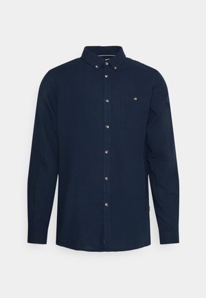 Tmavě modrá košile s dlouhým rukávem, button-down límcem, přední kapsou a kovovými knoflíky. Hladká, lehká tkanina s jednoduchým designem.