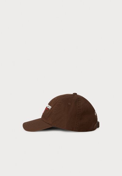 Brown cotton baseball cap with adjustable strap and white embroidered text on front and side, shown from the right side on a white background.