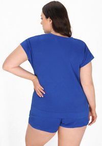 Blå tekstureret lounge sæt med en kortærmet bluse og shorts med et geometrisk mønster. Stoffet er glat og let.