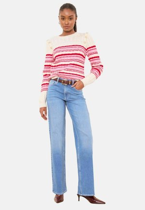Gestreifter Pullover in creme, rot und rosa Tönen; Rundhalsausschnitt; kombiniert mit hellblauen Jeans mit geradem Bein und dunkelbraunen Schuhen mit Absatz.