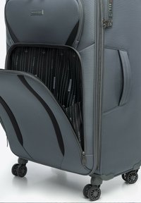 Grijze hard-shell koffer met een textuur oppervlak. Bevat een ritsvak aan de voorkant, vier zwarte wielen en een patrooninterieur.