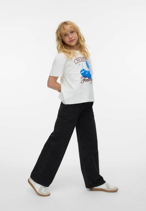 Vit t-shirt med korta ärmar, blått grafiskt mönster och text, kombinerad med svarta vida byxor och vita sneakers med gråa detaljer.