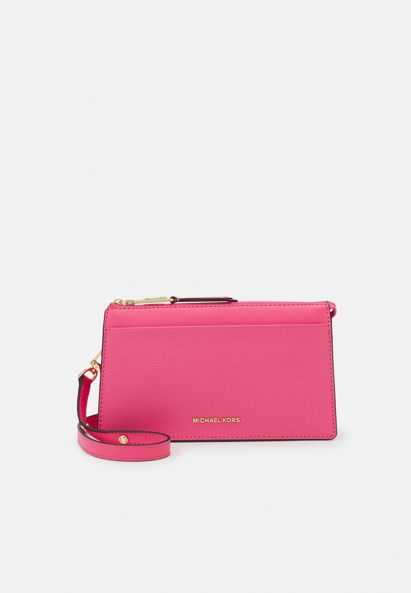 Pochette Michael Kors rose vif avec sangle poignet et fermeture éclair dorée sur un fond clair uni.