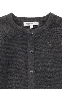 Grå stickad babykofta med rund nacke, två svarta knappar och en liten broderad logotyp på vänster sida. Storleksetikett synlig.