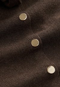 Tissu côtelé marron foncé avec trois boutons ronds dorés brillants disposés verticalement.