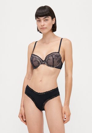 Zwart kanten bh met beugel en bijpassende slip. De bh heeft gegolfde randen en verstelbare bandjes; de slip heeft een kanten rand.