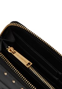 Črni denarnica z zadrgo zlatega tona in z zadrgo, na kateri je vgravirano "KARL LAGERFELD", z notranjim predalom in režami za kartice.