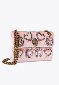 Różowa torebka z pikowanego aksamitu z sercowym i owalnym kamieniem szlachetnym, srebrnymi akcentami oraz łańcuszkowym paskiem. Posiada dekoracyjną klamrę.