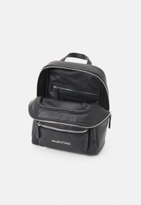 Czarny skórzany plecak z teksturowanym, pikowanym wzorem, srebrnymi zamkami błyskawicznymi, przednią kieszenią na suwak oraz przestronną komorą wewnętrzną.