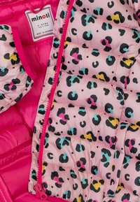 Chaleco acolchado rosa con cierre frontal, que presenta un patrón de leopardo colorido en negro, turquesa, amarillo y acentos en rosa.