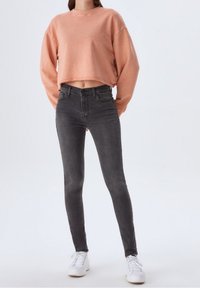 Sweat-shirt rose court à manches longues ; jean skinny gris taille haute ; baskets blanches. Design simple avec peu de détails.