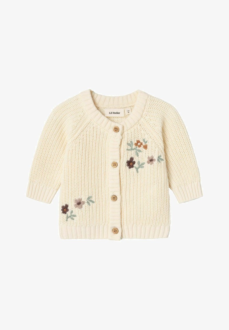 Strikket cremet cardigan med korte ærmer, træknapper og blomsterbroderi i pink, brun og grøn på den nederste venstre side.