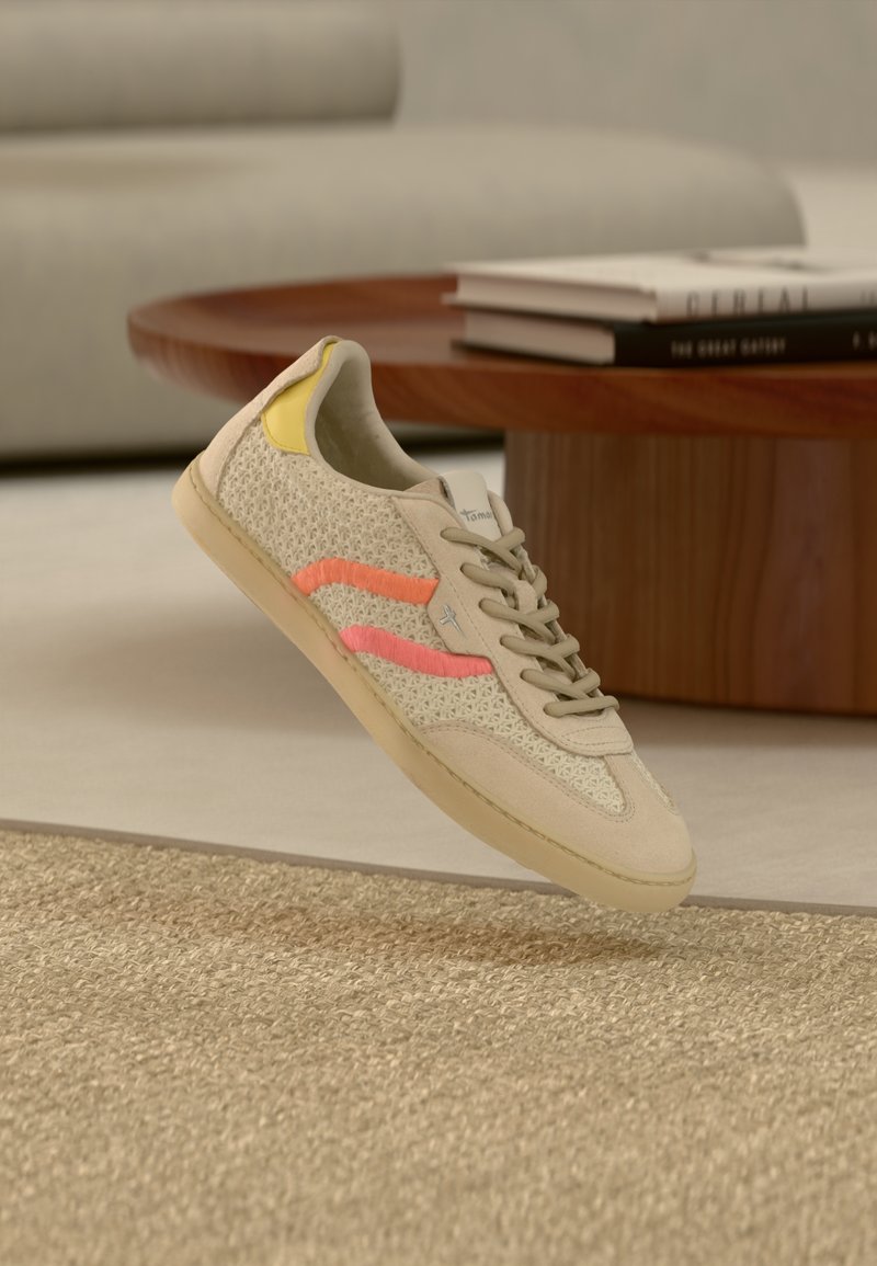 Baskets beiges avec une tige en mesh texturé, comprenant des accents roses et jaunes, bout rond, et semelle en caoutchouc beige. Les lacets sont gris clair.