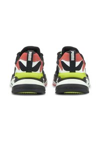 Baskets noires et rouges avec une tige texturée, des accents blancs prononcés et une semelle vert vif. Comprend une languette noire au talon.