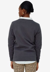 Gray sweatshirt with a crew neck and ribbed cuffs. The back features a white collar. Paired with leopard print leggings.