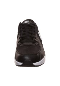 Scarpa sportiva nera con tomaia in rete e dettagli in pelle. Presenta il logo swoosh bianco, lacci rotondi e una suola in gomma texturizzata.