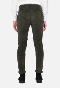 Pantaloni in velluto a coste verde slim fit, con tessuto testurizzato, orli arrotolati e tasche laterali, abbinati a stivaletti neri.
