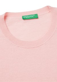 Jasnoróżowy sweter z prążkowanym dekoltem, wykonany z miękkiego materiału; ma zieloną metkę z napisem "UNITED COLORS OF BENETTON."