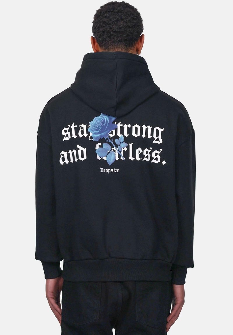 Schwarzes Sweatshirt mit Kapuze, auf dem Rücken mit weißem Text "Bleib stark und furchtlos" sowie einer blauen Rosen-Grafik. Weicher Stoff, lässiges Design.
