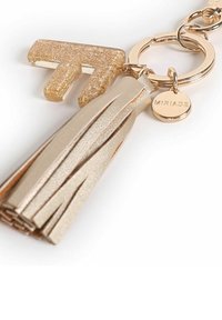 Portachiavi dorato con un'attaccatura a forma di lettera 'T' glitterata, un nastro metallico e un piccolo tag circolare inciso con la scritta "Miriade."