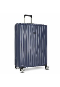 Valigia rigida blu navy con superficie a righe, manico telescopico, quattro ruote piroettanti e un badge con il logo sul davanti.