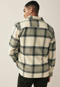 Kreemivärvi flanellshirt, millel on roheline ja tume sinine ruuduline muster, pikad varrukad, nööpidega kinnitamine ja kumer hem. Tekstuuriga kangas.
