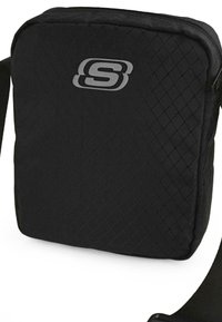 Bolso de hombro rectangular negro hecho de nailon texturizado, que presenta un patrón de diamante y un logo plateado en la parte frontal. Incluye una correa ajustable.