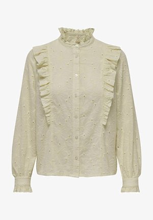 Lysegul bluse med en høj flæsekrave, knaplukning foran og flæse detaljer langs venstre skulder. Har blomsterbroderi og lange ærmer.