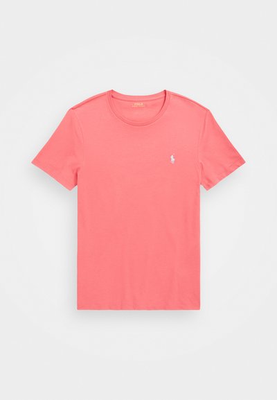 Krátky rukáv, tričko s okrúhlym výstrihom v koralovej farbe, vyrobené z bavlny s hladkou textúrou, s malým bielym logom na ľavej strane hrudi.