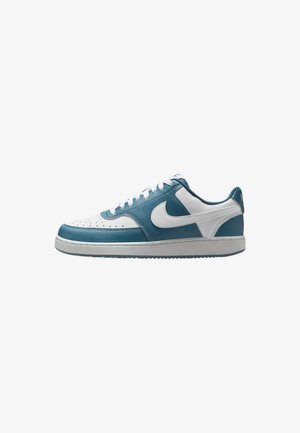 Sneakers Nike con una parte superiore in pelle bianca e teal, punta perforata, logo swoosh a contrasto e suola in gomma con grip testurizzato.