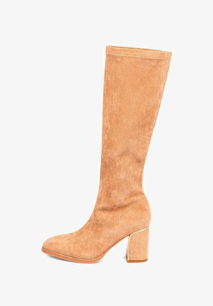 Helle Wildleder-Knöchelstiefel mit abgerundetem Zeh, Blockabsatz und dezenten Nahtdetails auf einem weißen Hintergrund.