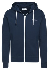 Sudadera con cremallera color azul marino hecha de tela suave, presenta una cremallera blanca, cordones, bolsillos frontales y un pequeño logo en el lado izquierdo del pecho.