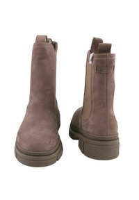 Bruine suède enkelboots met elastische zijkanten, trekhaakjes en een dikke rubberen zool. Voorzien van tonal stiksels en een afgeronde teenontwerp.