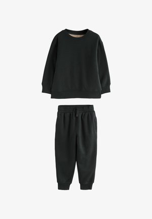 Juodas megztinis su apvaliu iškirpimu ir įgertu rankogaliu, derinamas su atitinkančiomis juodomis kelnių kelnėmis, turinčiomis elastingą juosmenį ir siaurėjančiomis kojomis.