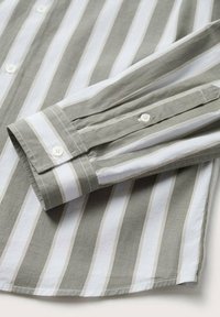 Camicia a righe con tessuto alternato verde oliva e bianco, dettaglio dei polsini con bottone e texture liscia, dotata di colletto classico.