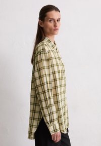 Long-sleeve, button-up shirt in yellow and green plaid pattern, featuring a relaxed fit, side slits, and collared neck design.