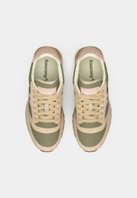 Beige and green Saucony sneakers with a smooth texture, featuring pink accents, round toe, and lace-up front. Ventilated tongue design.
