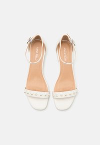 Hvite sandaler med bred stropp og små perledetaljer, åpen tå-design, ankelstropp med spenne og en glatt såle.