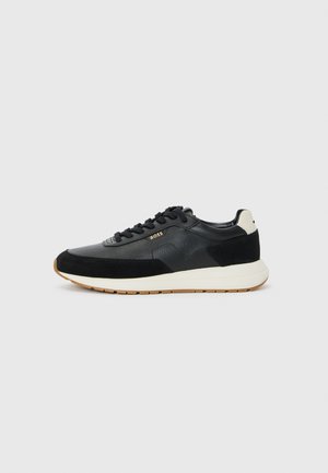 Black sneaker featuring a mix of textured leather and suede, with a white midsole and gum rubber outsole. Laces in matching black.