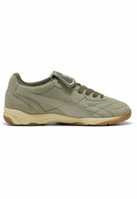 Baskets en suede vert olive avec une semelle beige clair, présentant des détails de couture et une étiquette de marque sur la languette. Design léger et rembourré.