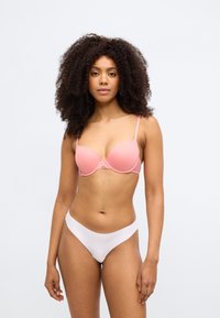 Ροζ ανοιχτό σουτιέν με επένδυση, πλεγμένη πλάτη, ρυθμιζόμενους ιμάντες και ασημένιο κούμπωμα. Λευκό σλιπ με λεία υφή και μινιμαλιστικό σχεδιασμό.