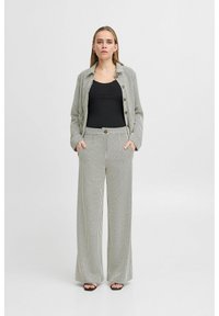 Černobílý set zahrnující blazer a kalhoty s širokými nohavicemi. Blazer má zapínání na knoflíky a kapsy; kalhoty mají vysoký pas.
