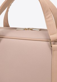 Beige leren handtas met gestructureerd oppervlak, strakke vorm, dubbele handvatten, goudkleurige hardware en bovenste ritssluiting.