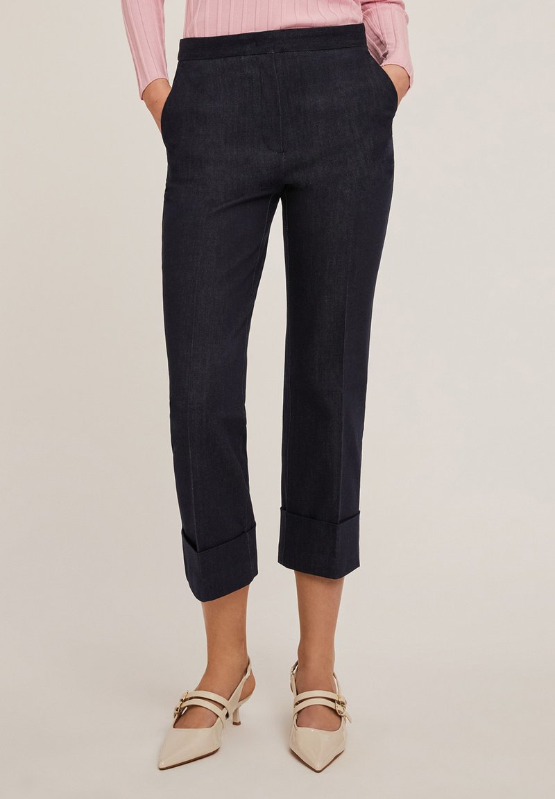 Pantalons cropped navy avec une texture lisse et des ourlets retroussés. Conçus avec des poches latérales, idéaux pour un style décontracté ou formel.