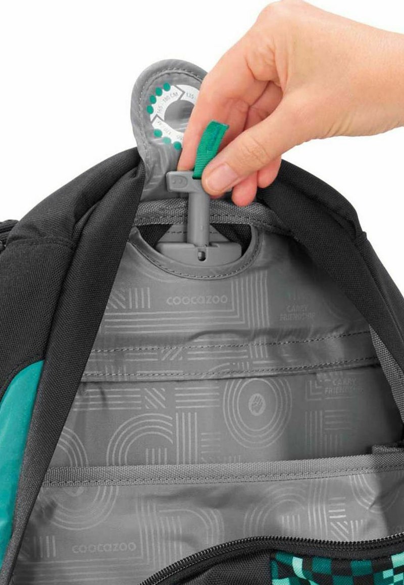 Intérieur du sac à dos montrant un revêtement �à motifs gris et un mécanisme de sangle réglable. Présente des accents turquoise et des compartiments zippés.