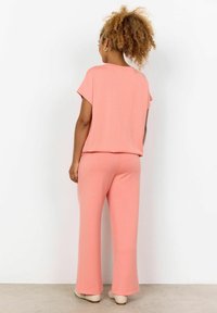  Lichtroze tweedelige outfit van zachte stof, met een relaxte fit top met korte mouwen en wijde broek zonder zichtbare patronen.